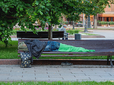 俄罗斯莫斯科-2018 年 6 月 4 日。无家可归的人睡在街边的长椅上。