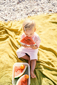 小女孩在毯子上吃西瓜