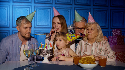 小女孩在蛋糕上吹蜡烛许愿，玩得开心，和家人一起庆祝生日聚会
