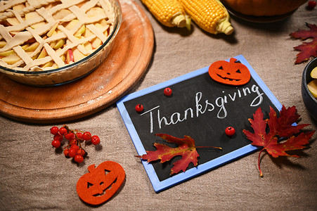 黑板上写着感恩节，旁边是节日馅饼，桌子上有玉米和南瓜的秋收
