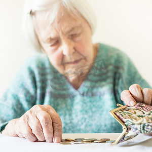 坐在桌旁忧心忡忡的老妇人数着钱包里的钱。