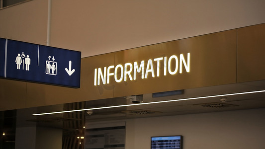 信息点柜台上贴有“信息”霓虹灯标签，机场大厅悬挂着厕所和电梯象形图。