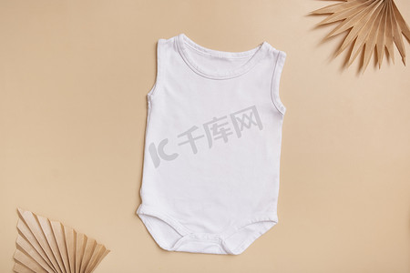 白色婴儿紧身衣模型，用于米色背景上的徽标、文字或设计，棕榈叶顶视图