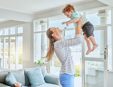 家庭预算表摄影照片_家庭、爱和能量，母亲和儿子在家里的休息室玩耍、亲密和举起幼儿在空中玩耍。
