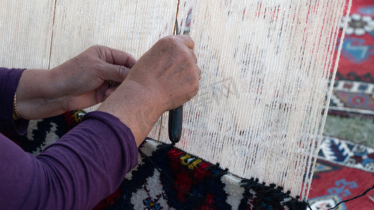 女手在织机、纺织工业上编织地毯