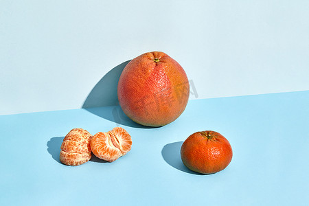 水果图案装饰摄影照片_新鲜水果、葡萄柚和柑橘的组合物，一半去皮的柑橘