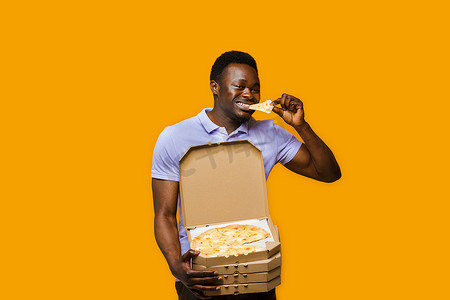 有趣的黑色快递员吃着一块披萨，拿着 4 个披萨盒。