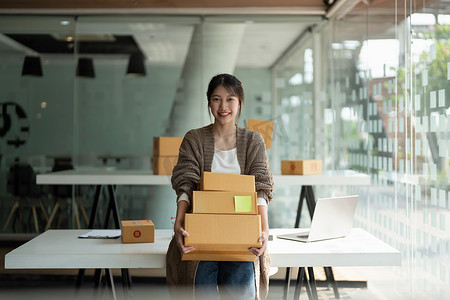 开办小型企业的中小企业主女企业家拿着一叠箱子在线查看订单，准备包装箱子，卖给客户，网上中小企业的商业理念。