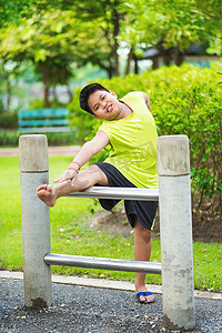 铁运摄影照片_亚洲运动男孩在花园里的铁条上伸展