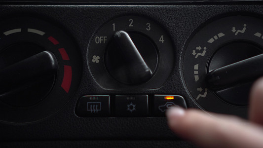 温度按钮摄影照片_女子打开风扇，按下车内通风按钮。