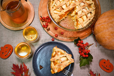 静物：自制南瓜派配苹果、脆皮和一杯热茶，周围环绕着秋天的落叶。