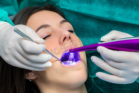 医用外口口罩摄影照片_牙医用 LED 治疗灯对女孩预防蛀牙。