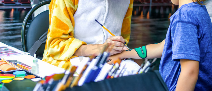 年轻女孩艺术家在孩子的手上画龙。