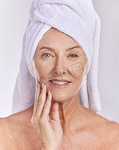 护肤、健康和美容，一位高级女性，头上戴着毛巾，脸上带着微笑，洗完澡后照顾好自己的皮肤。