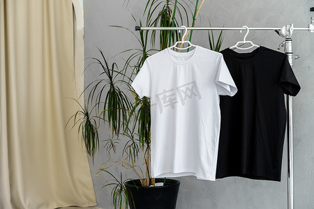衣架上的白色和黑色 T 恤用于设计展示