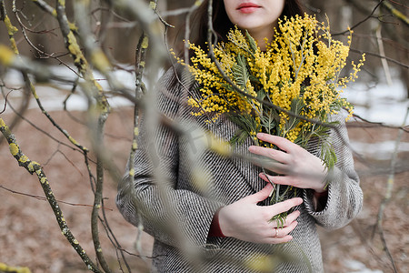 自然背景下捧着一束春含羞草花的女人