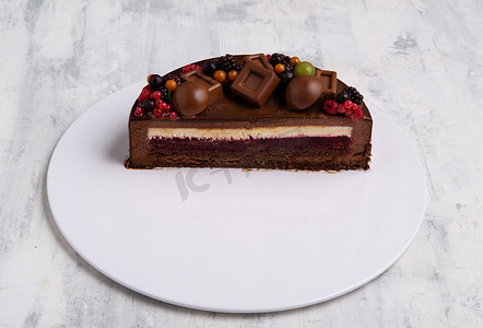 用浆果装饰的巧克力釉蛋糕的一半的角度拍摄。