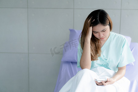 护士病人摄影照片_女病人在医院接受治疗，在病房的床上承受着压力