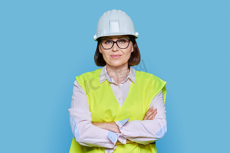 蓝色背景中身穿防护头盔背心的女工业工人画像