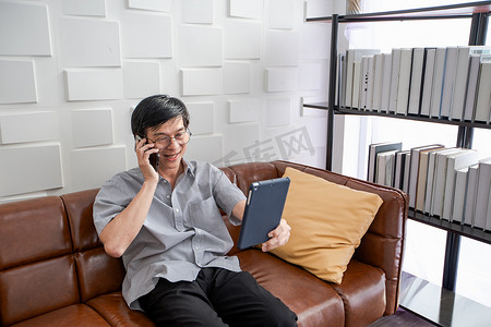 i平板壁纸摄影照片_亚洲老人在客厅的沙发上玩平板电脑和视频通话