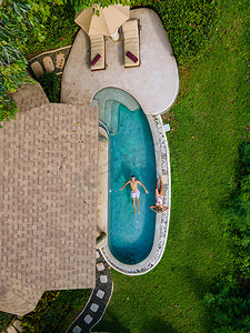 一对欧洲男人和亚洲女人在泰国的无边泳池中眺望大海，泰国的豪华假期，私人泳池别墅