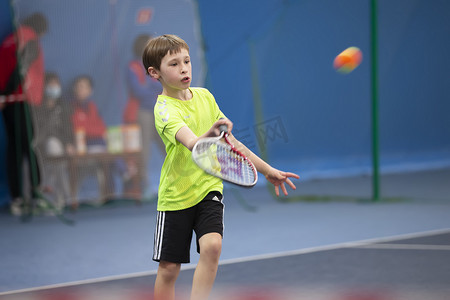 一个拿着网球拍的男孩在球场上打网球。