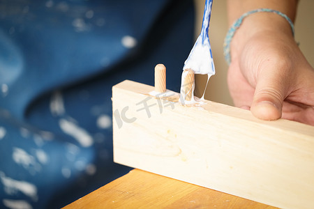 木工操作员正在使用胶水将木质部件组装在一起，为客户组装和建造木桌