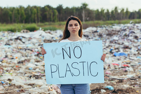 斗争摄影照片_女志愿者在垃圾填埋场举着无塑料海报，积极分子与环境污染作斗争