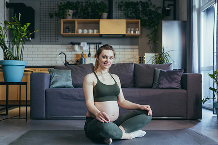 一名孕妇在家里以莲花的姿势冥想和练习瑜伽
