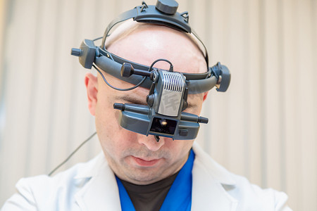 男性眼科医生用双目检眼镜检查患者的视力