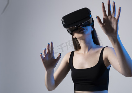 年轻迷人的黑发女性戴着 VR 护目镜，在虚拟现实视频游戏中享受令人惊叹的体验和乐趣。
