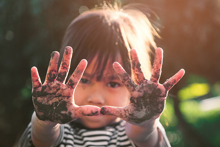 可爱的小女孩在后院植树时微笑着展示她沾满泥的手。
