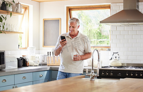 在家里的厨房里阅读短信、在线新闻或浏览互联网时，老人、早上喝咖啡和打电话看起来很开心。