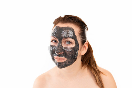 一位女士洗完澡后的特写肖像，她的眼睛和嘴唇周围脸上戴着黑色化妆泥面膜