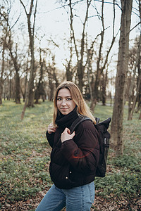 绿色大气摄影照片_背着背包的女性旅行者，看着令人惊叹的森林、旅行癖旅行概念、文字空间、大气史诗