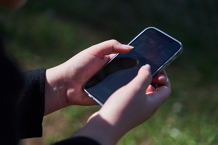 黑山扎布利亚克 — 2021年5月28日：草地背景下女性手握智能手机