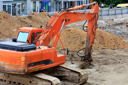 重型建筑挖掘机履带式铲斗在城市街道上的集尘器维修过程中挖出一条沟渠。