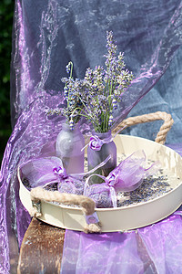 清新薰衣草摄影照片_花瓶中的淡紫色薰衣草和薰衣草香袋，托盘上的雪纺袋，静物