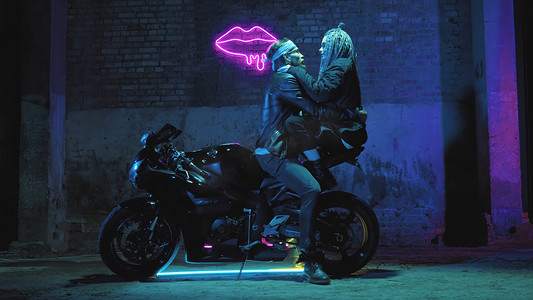 一个恋爱中的女孩和一个男人坐在超级运动摩托车上，在霓虹灯的背景下调情和拥抱