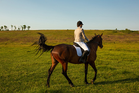 在绿色田野上骑马的年轻女子