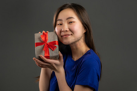 兴奋的亚洲女孩收到带蝴蝶结的礼盒。