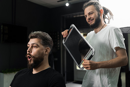 快乐而惊讶的留着胡子的男人在理发店照镜子。