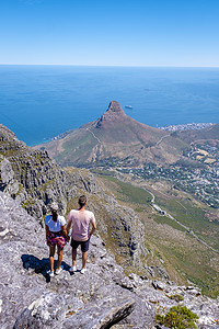 眺望山摄影照片_一对男女在桌山顶上，从南非开普敦的桌山眺望，从桌山开普敦远眺海洋和狮子头