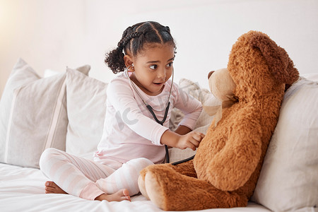 学习带听诊器的孩子在她的卧室里用爱、医疗保健或儿童发展检查泰迪熊。