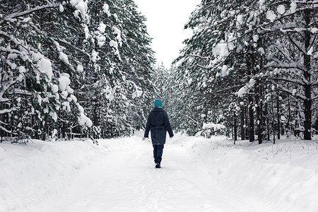 一个女孩走在冬天白雪皑皑的森林里。