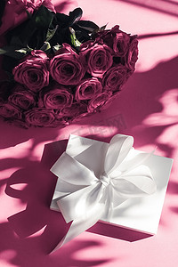惊喜礼盒摄影照片_豪华假日丝绸礼盒和粉色背景玫瑰花束、浪漫惊喜和鲜花作为生日或情人节礼物