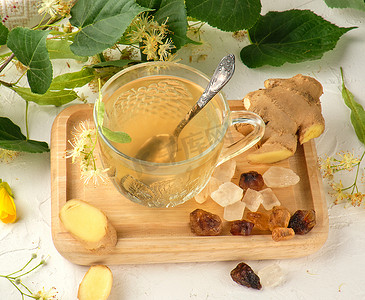 白木上的透明杯子，配有生姜和菩提树的茶