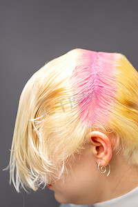 年轻的白人妇女在美容院里把发根染成粉红色。