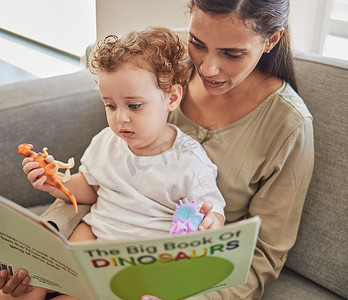 家庭、婴儿和母亲和男孩一起在客厅的沙发上读书。