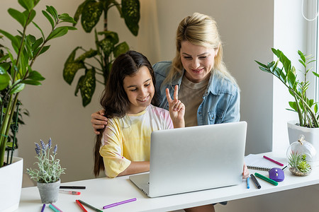 美丽的母亲和孩子看着笔记本电脑屏幕，使用应用程序教育计划在厨房里度过时光，选择卡通片，教孩子使用电脑，控制女儿在互联网网络空间概念上观看的内容